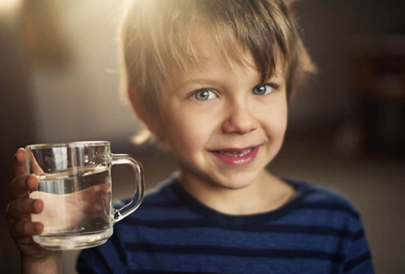 Photo d'un enfant avec un verrre d'eau filtré avec notre osmoseur Osmodyn Plasma marin