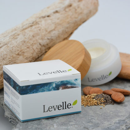Photo d'un pot de crème visage Levelle 100% Naturelle ouvert mis en situation avec son packaging